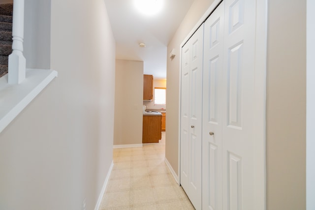 corridor with light floors, baseboards, and stairway