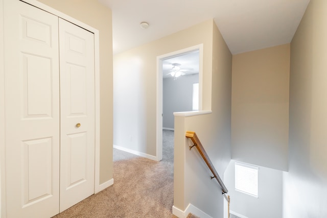 hallway with baseboards, light carpet, visible vents, and an upstairs landing