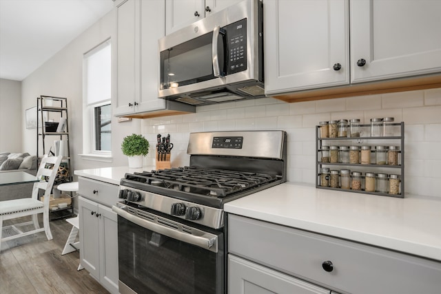 kitchen with white cabinetry, appliances with stainless steel finishes, light countertops, and backsplash