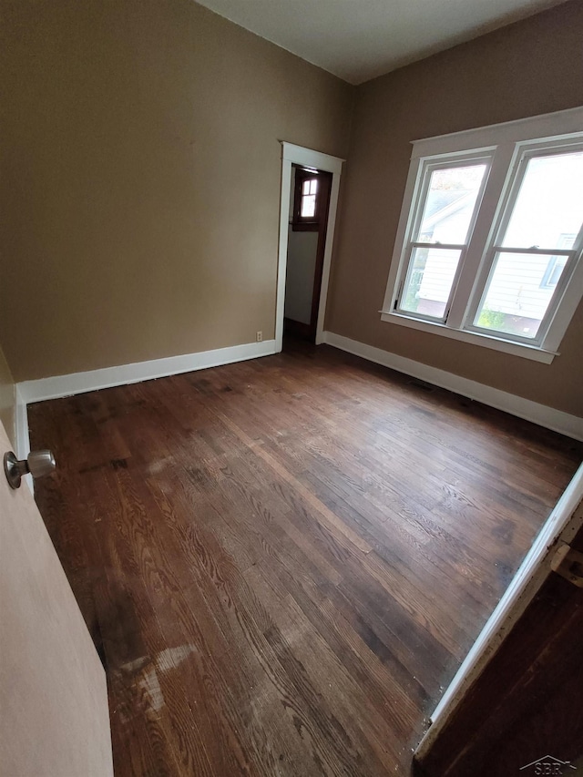 spare room featuring dark wood-type flooring and baseboards