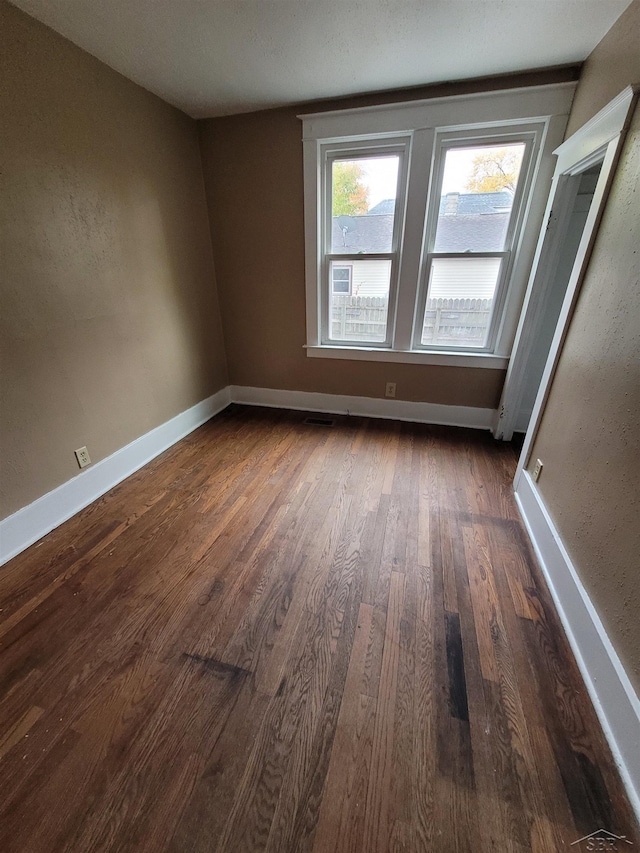 empty room with baseboards and dark wood finished floors