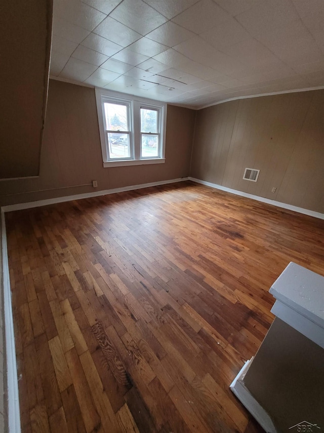 spare room with baseboards, visible vents, and wood finished floors