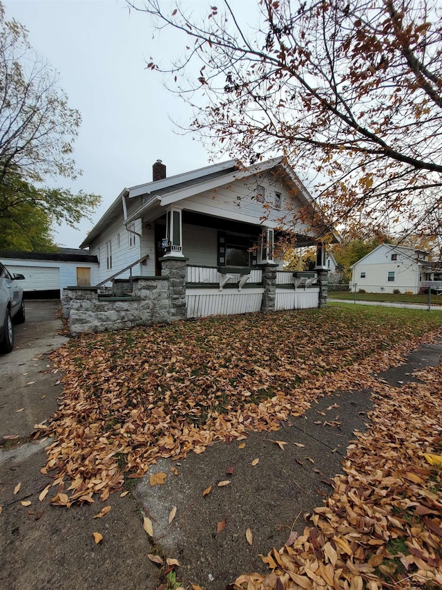 bungalow-style home featuring a garage, covered porch, and a chimney