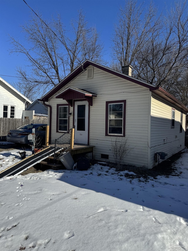 view of front of house featuring a chimney and fence