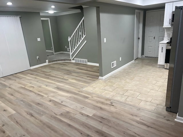 basement with ornamental molding and light hardwood / wood-style floors