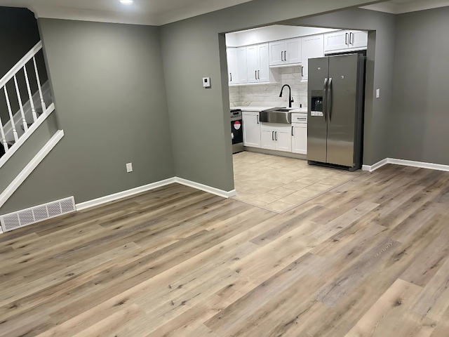 kitchen featuring sink, white cabinetry, stainless steel fridge with ice dispenser, light hardwood / wood-style floors, and decorative backsplash