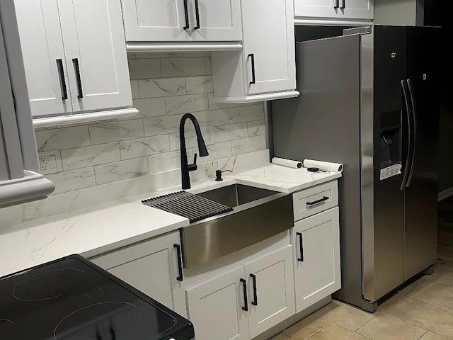 kitchen with sink, light stone counters, range with electric stovetop, stainless steel fridge, and white cabinets