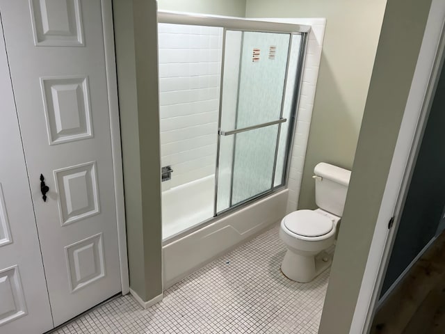 bathroom featuring tile patterned flooring, toilet, and shower / bath combination with glass door