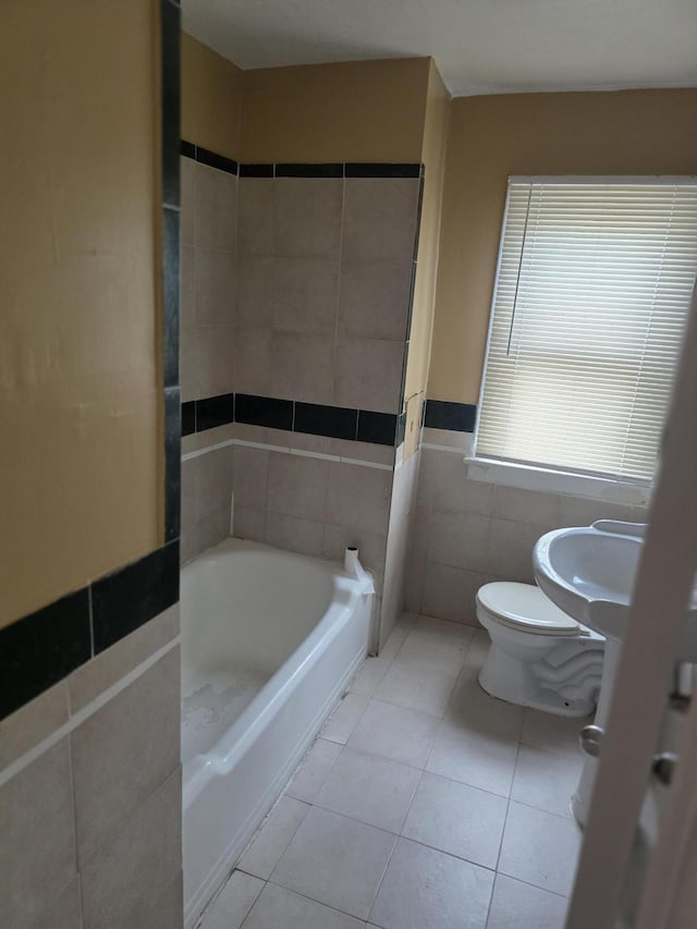 20529 Irvington St, Highland Park, MI 48203 - bathroom with tile patterned floors, a bath, wainscoting, tile walls, and toilet