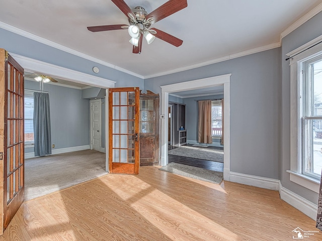 empty room featuring french doors, crown molding, plenty of natural light, and light hardwood / wood-style flooring