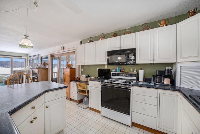 kitchen featuring a textured ceiling, white range with gas stovetop, white cabinets, and pendant lighting