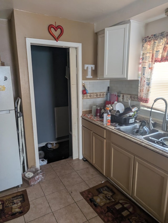 kitchen featuring light tile patterned floors, sink, white cabinetry, white refrigerator, and tasteful backsplash