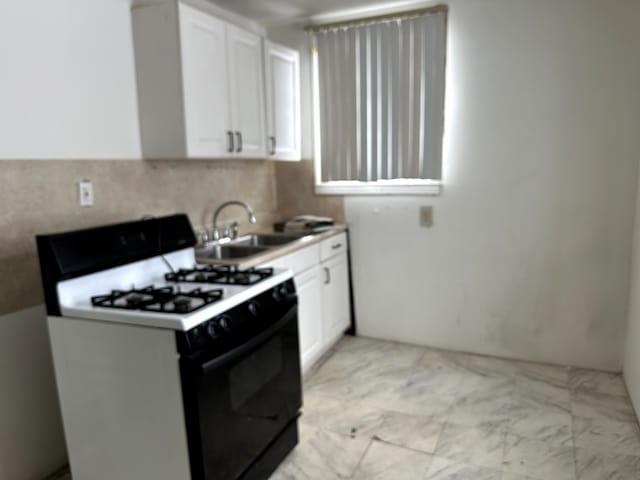 kitchen with sink, white cabinetry, and range with gas cooktop