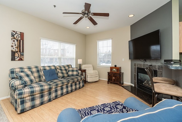 living room featuring a fireplace, ceiling fan, and wood-type flooring