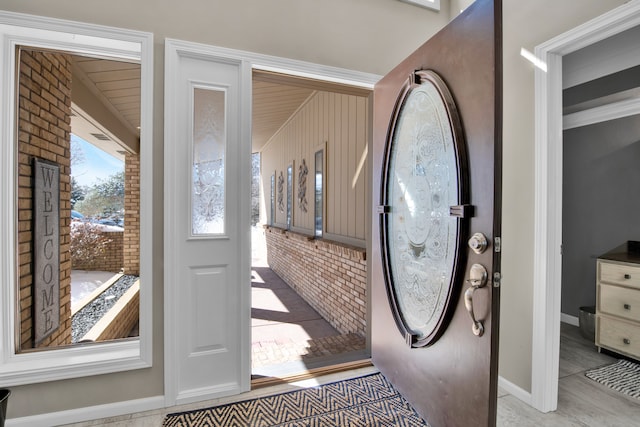 entrance foyer with baseboards and brick wall