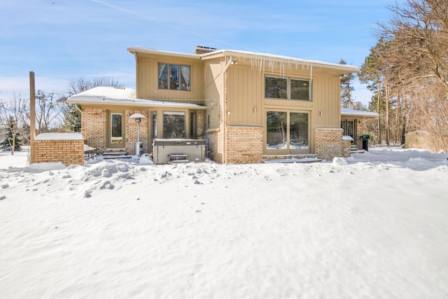 exterior space featuring brick siding and a hot tub