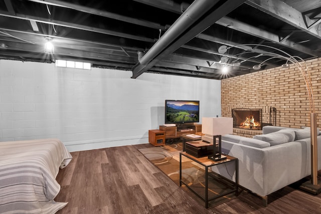 living room with brick wall, a fireplace, and wood finished floors