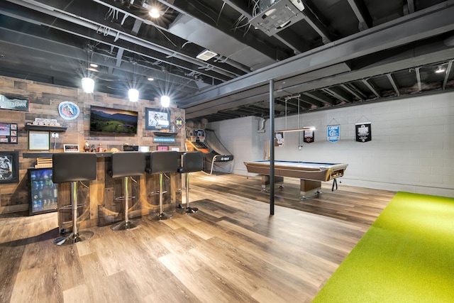 game room featuring concrete block wall, pool table, a dry bar, and wood finished floors