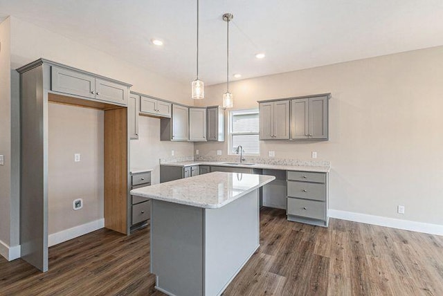 kitchen featuring a kitchen island, a sink, dark wood-type flooring, gray cabinetry, and decorative light fixtures