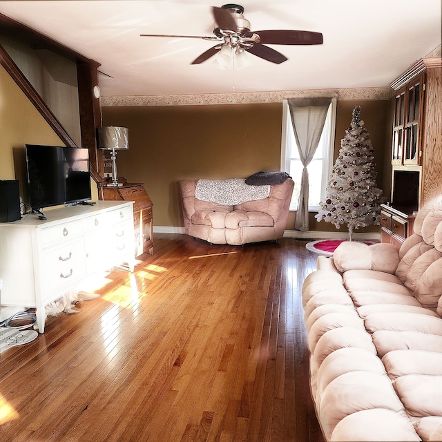 living area featuring baseboards, ceiling fan, and hardwood / wood-style flooring