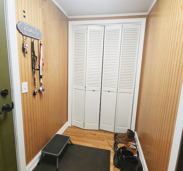 entryway with light wood-style flooring and ornamental molding