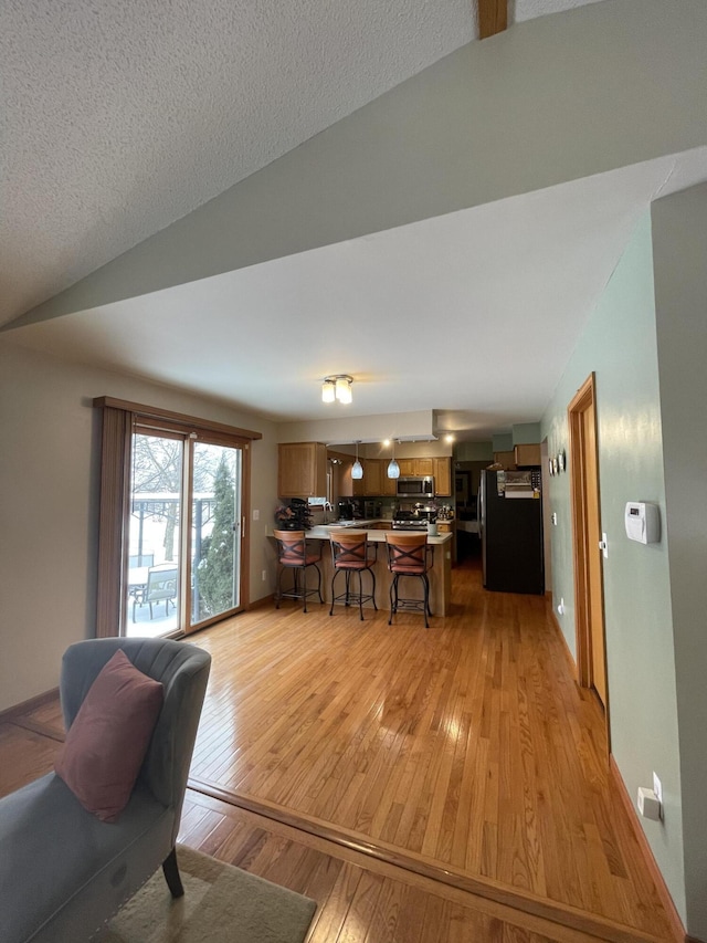 interior space with light hardwood / wood-style flooring, a textured ceiling, and lofted ceiling