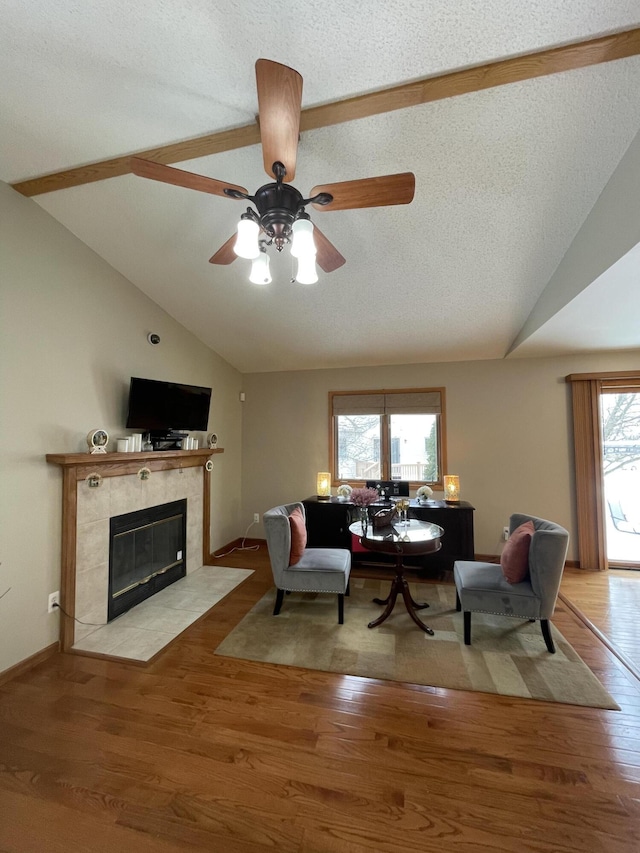 living room with light wood-type flooring, lofted ceiling, a textured ceiling, and a fireplace