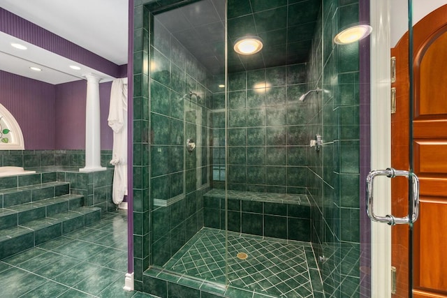 bathroom with tile patterned floors, ornate columns, tile walls, and a shower with door