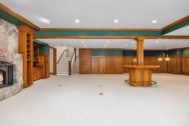 carpeted living room with ornamental molding and a stone fireplace