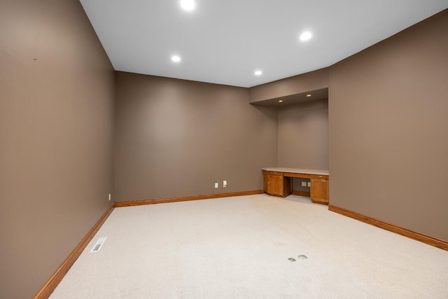 carpeted empty room with built in desk