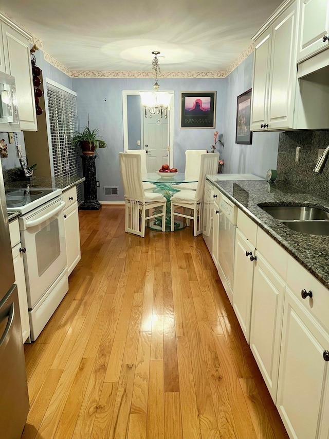 kitchen featuring white appliances, light wood-type flooring, decorative light fixtures, sink, and white cabinetry