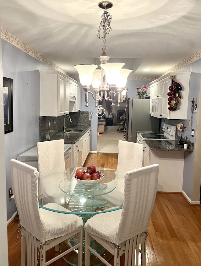 dining area featuring sink, a chandelier, and light hardwood / wood-style flooring