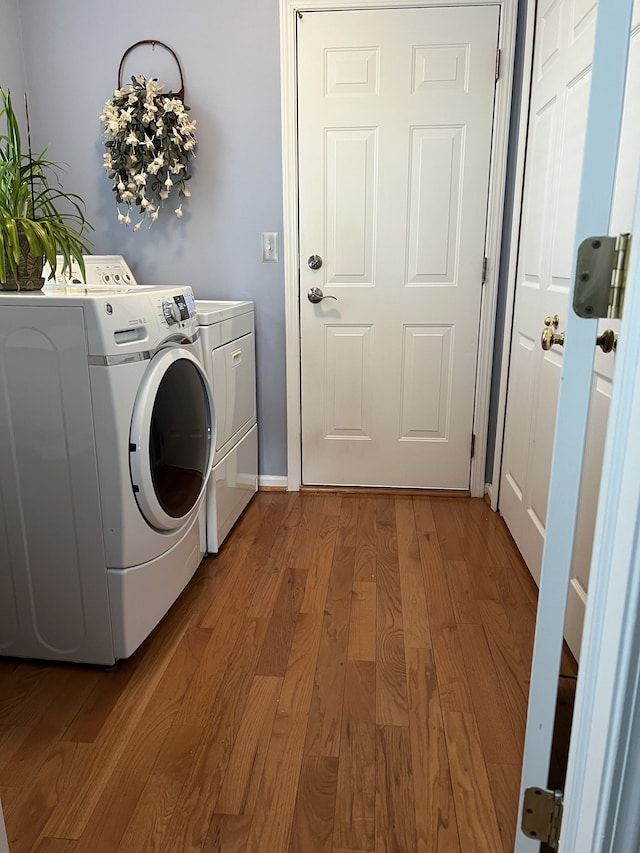 clothes washing area with washing machine and dryer and light hardwood / wood-style flooring