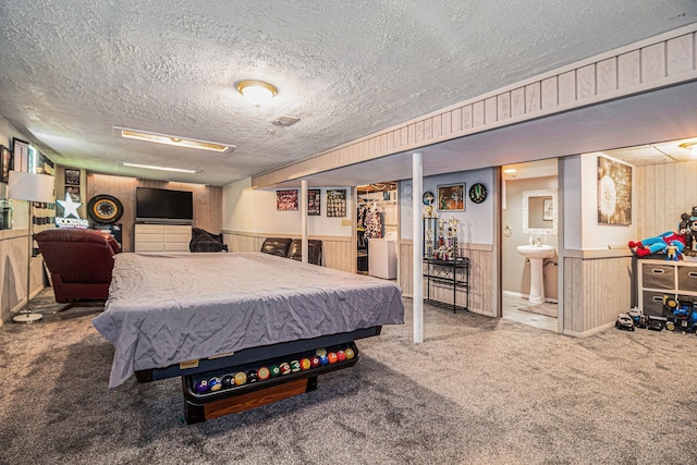 carpeted bedroom with a wainscoted wall, a textured ceiling, and wooden walls