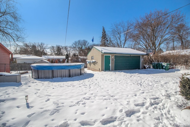 snowy yard with a garage, an outdoor structure, and fence