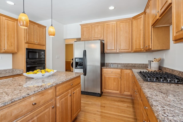 kitchen with hanging light fixtures, light hardwood / wood-style floors, light stone countertops, and black appliances