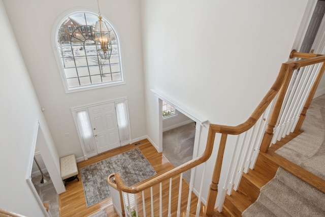 foyer entrance with light hardwood / wood-style flooring, a chandelier, and a towering ceiling