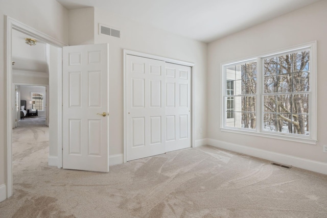 unfurnished bedroom with ornamental molding, light carpet, and a closet