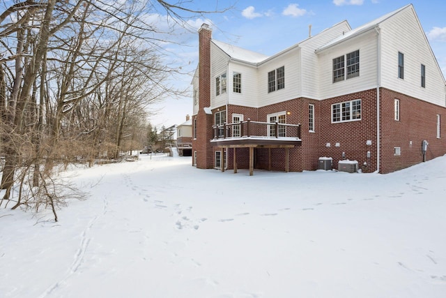 snow covered property with central AC unit and a wooden deck