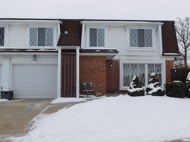 view of front facade featuring brick siding, an attached garage, and mansard roof