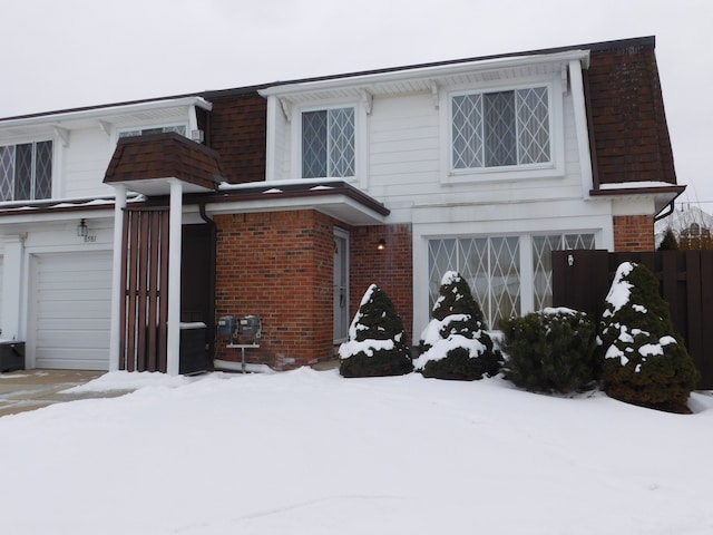 view of front of house with a garage, fence, mansard roof, and brick siding