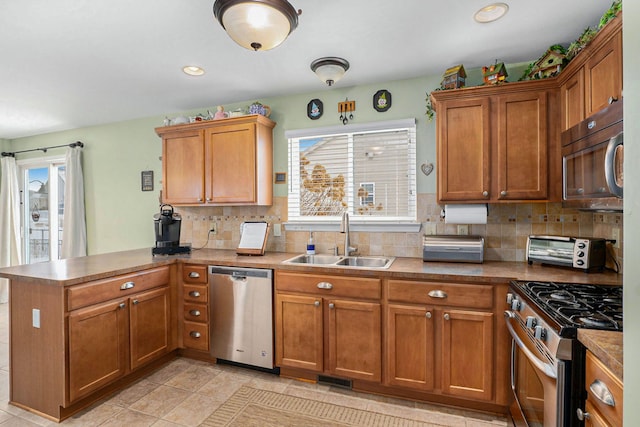 kitchen featuring appliances with stainless steel finishes, sink, kitchen peninsula, and a healthy amount of sunlight