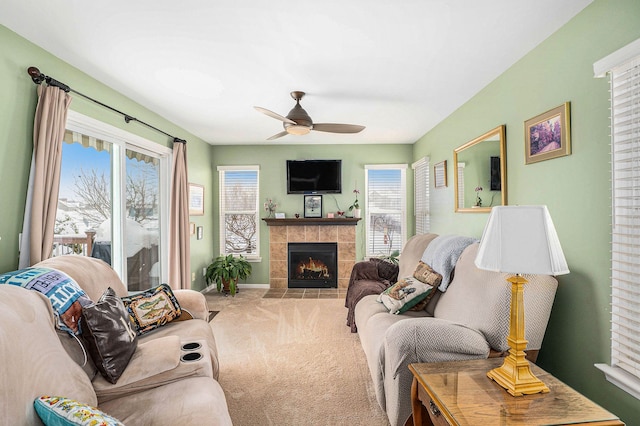 carpeted living room with ceiling fan, a tile fireplace, and a healthy amount of sunlight