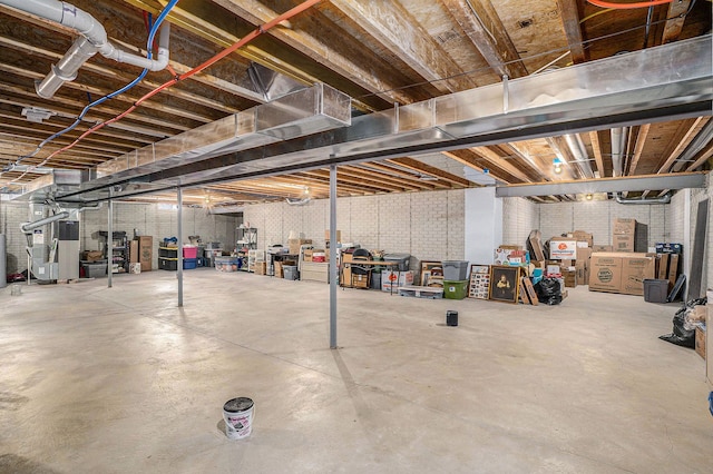 basement featuring heating unit and brick wall