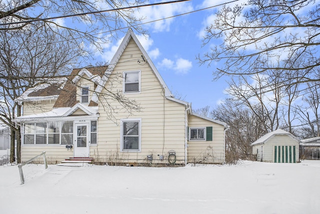 snow covered back of property with a storage unit