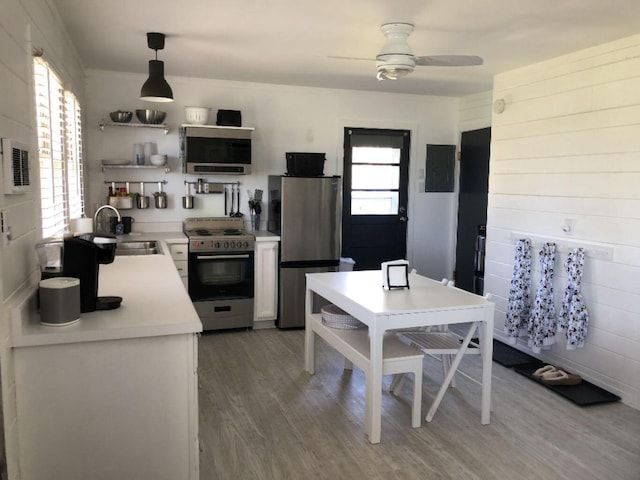 kitchen featuring decorative light fixtures, electric panel, sink, appliances with stainless steel finishes, and hardwood / wood-style floors