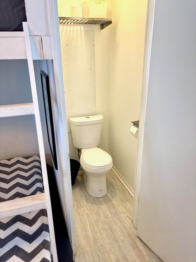 bathroom with wood finished floors, toilet, and baseboards