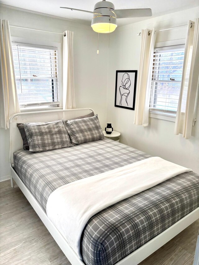 bedroom with ceiling fan, wood finished floors, and baseboards