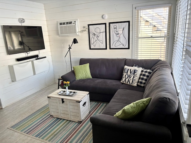 living area featuring wood finished floors, plenty of natural light, and a wall mounted AC