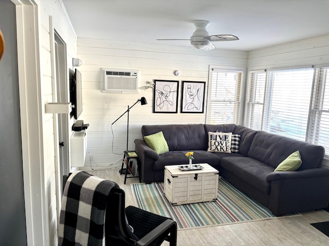 living area featuring a wall unit AC, a ceiling fan, and wood finished floors